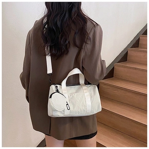 Vista lateral de un bolso Boston de nailon beige llevado en bandolera por una modelo