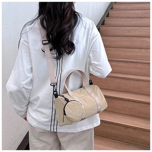 Detalle de bolso boston de lona beige con mini monedero en la espalda del modelo