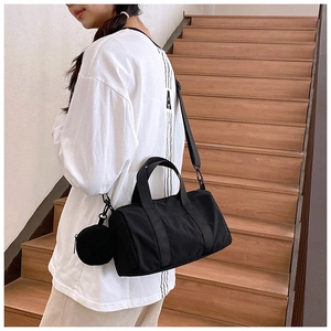 Detalle de bolso cilíndrico negro con mini estuche llevado por modelo en una escalera