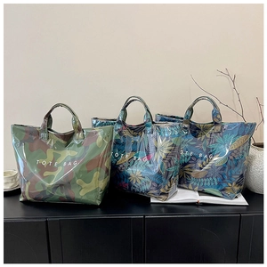 Detailed view of three large glossy tote bags with tropical leaf and camouflage patterns