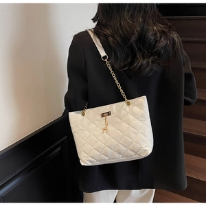 Detailed view of white quilted tote bag with gold chain strap and deer charm accessory