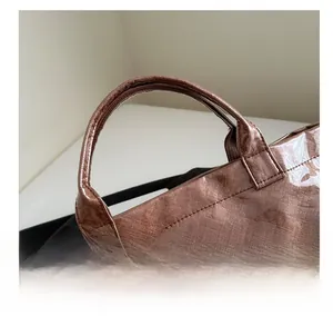 Detalle de un bolso tote marrón con asa reforzada y acabado de tela plisada texturizada