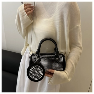 Detalle de bolso cilindro negro con brillantes, tachuelas y mini monedero colgante