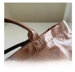 Detalle de costura reforzada en el asa de un bolso tote marrón con textura rugosa