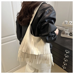 Détail d'un sac bandoulière blanc avec de longues franges porté par un mannequin