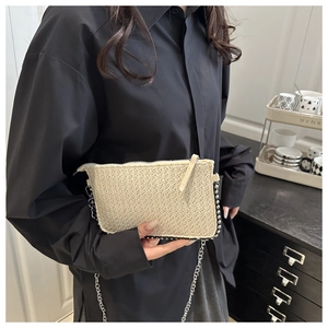 Détail de la pochette tressée beige avec bandoulière chaîne et bordure à perles