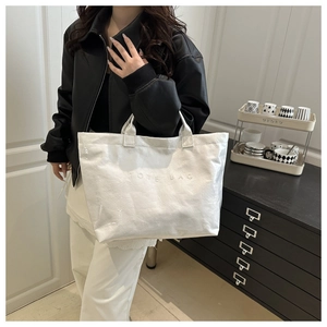 Detail of white glossy tote bag featuring embossed TOTE BAG text and large capacity
