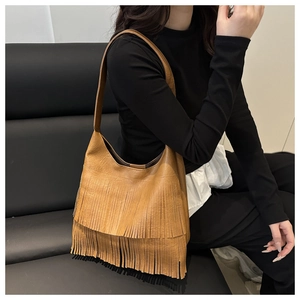 Détail du sac cabas marron à franges avec pompons bohèmes et texture en cuir