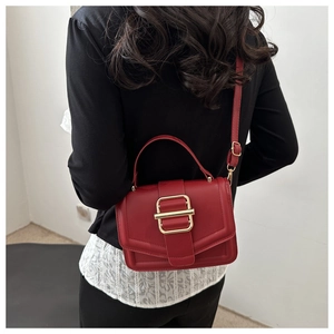 Détail du sac à main rouge en cuir avec grande boucle dorée et bandoulière réglable