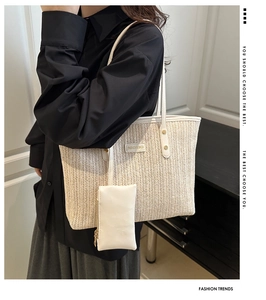 Detail of straw woven tote bag featuring a leather fashion label and small hanging pouch