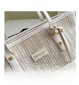 Detail of straw woven tote with leather trim, fashion label, and gold rivet accents