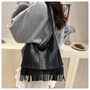 Détail du sac à bandoulière en cuir noir texturé avec décoration de franges élégantes