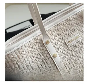 Close-up of woven straw tote bag texture with gold metal rivets and leather fashion tag