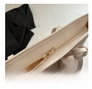 Macro shot of smooth gold zipper detail and woven texture on large cream tote bag