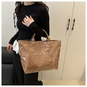 Close-up of a large transparent PVC tote bag with brown paper texture and white text
