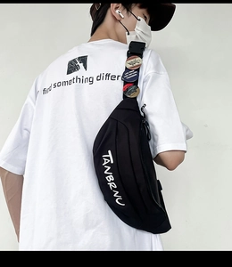 Detailansicht der schwarzen Nylon-Brusttasche mit weißem Logo und Vintage-Badges am Gurt