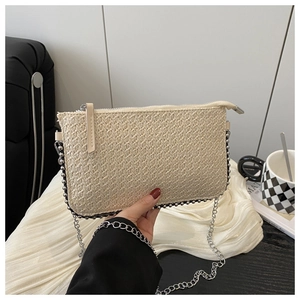 Détail de la pochette en paille beige avec bordure en perles et chaîne métal