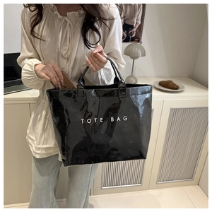 Borsa tote nera lucida con scritta bianca TOTE BAG in un accogliente ambiente domestico