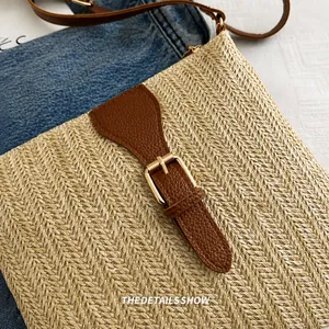 Close-up of beige woven texture with dark brown leather flap and gold buckle on crossbody bag