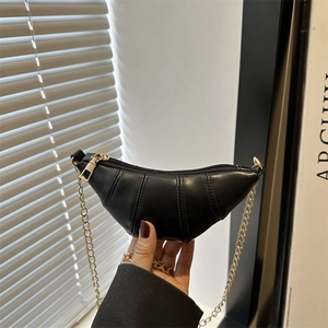 Détail d'un mini sac croissant noir avec bandoulière chaîne dorée et coutures verticales
