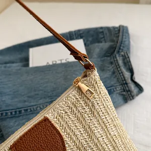 Close-up of woven straw shoulder bag with smooth golden zipper and brown leather detail