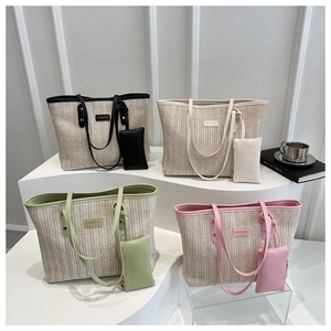 Detail of four multi-color woven straw tote bags with leather trim on display