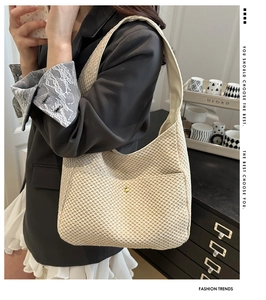 Détail d'un sac hobo tissé beige avec poche frontale et rivet doré porté par un mannequin