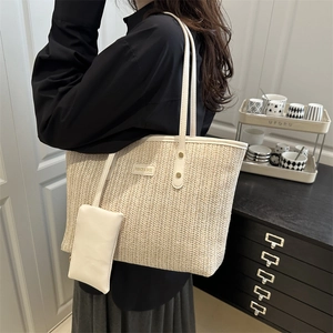 Fashionable woven straw tote bag with contrast shoulder straps and a mini matching pouch