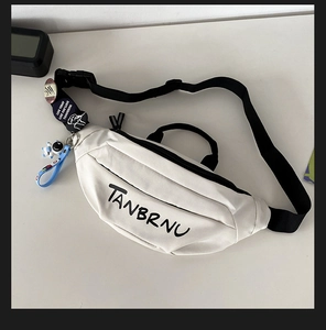 Detailansicht der cremeweißen Brusttasche mit Astronauten-Anhänger und Motiv-Buttons