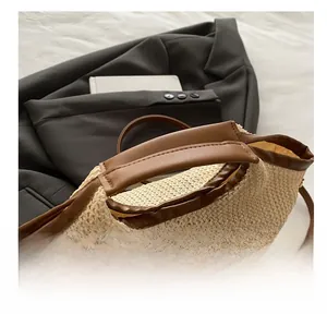 Détail d'un sac cabas en paille tissée avec poignées en cuir marron et finitions soignées
