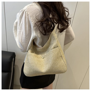 Détail de la texture en paille tressée et boucle dorée d'un sac de plage beige élégant