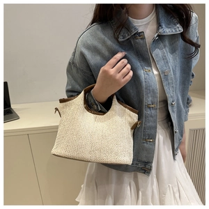 Détail du sac cabas en paille tissée avec garniture en cuir brun et boucles en métal