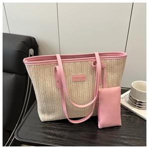 Detail of straw woven tote bag featuring pink leather handles and matching small pouch