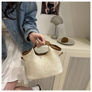 Détail du sac cabas en paille tissée avec garniture en similicuir marron et boucles en métal