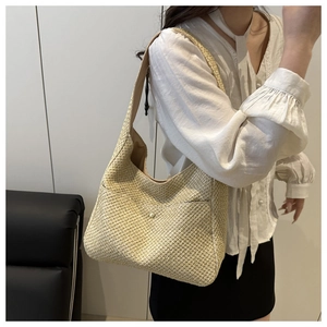 Détail d'un sac à bandoulière tressé beige avec poche avant et bouton-pression en métal doré