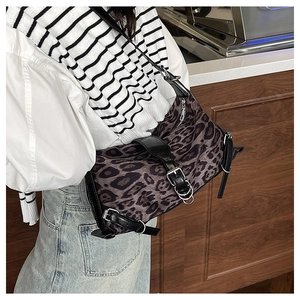 Detail of leopard print crossbody bag with black leather straps and silver metal buckles