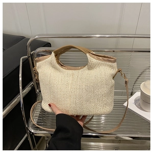 Détail d'un sac cabas en paille tissée avec poignées en cuir et bandoulière réglable