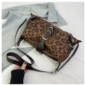 Detail view of leopard print tote bag with brown leather straps and silver metal buckles