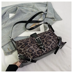 Close-up of leopard print tote bag featuring black leather trim and silver metal buckles