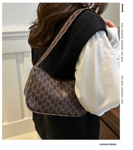 Brown vintage hobo bag with M-letter monogram pattern worn on model's shoulder
