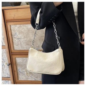 Détail du sac crème tissé avec bandoulière chaîne sur mannequin en veste noire