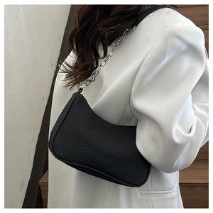 Detail of minimalist black underarm bag featuring a chunky silver chain strap and twill texture
