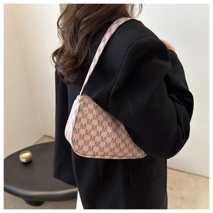 Detail showing pink crescent bag with M-letter print worn by model in black suit