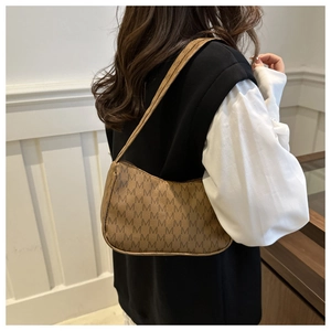 Detail of a brown monogram crescent bag worn on the shoulder with vintage M pattern