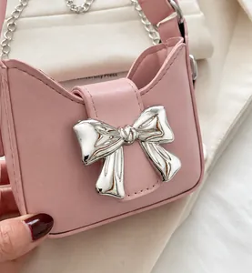 Close-up of pink leather handbag featuring a silver metal bow buckle and chain strap