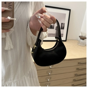 Dettaglio di una borsa a mezzaluna nera con cerniera dorata e finitura in pelle liscia opaca