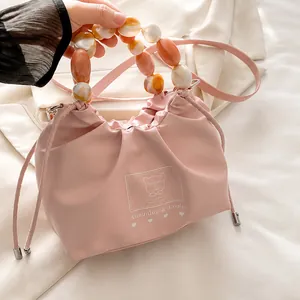 Detalle de bolso saco de satén rosa con cuentas de mármol ámbar y estampado de oso