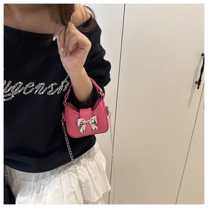Détail du mini sac à main rose avec boucle papillon argentée et bandoulière chaîne