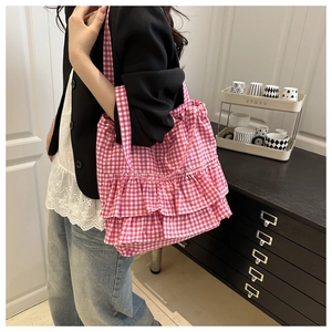 Detail of pink plaid canvas tote bag featuring layered ruffle accents and wide straps