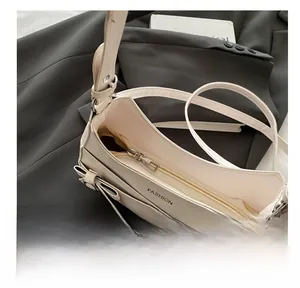 Détail d'une fermeture éclair en métal sur un sac bandoulière en cuir blanc cassé